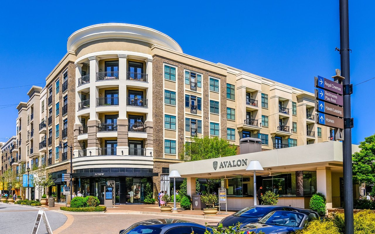 Avalon mixed-use building with apartment balconies, street-level shops, and directional signs.