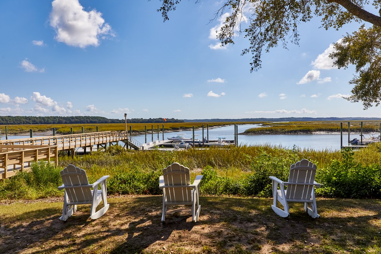 Waterfront at Moss Creek with Adirondack chairs, a boardwalk, docks, and marsh creek.