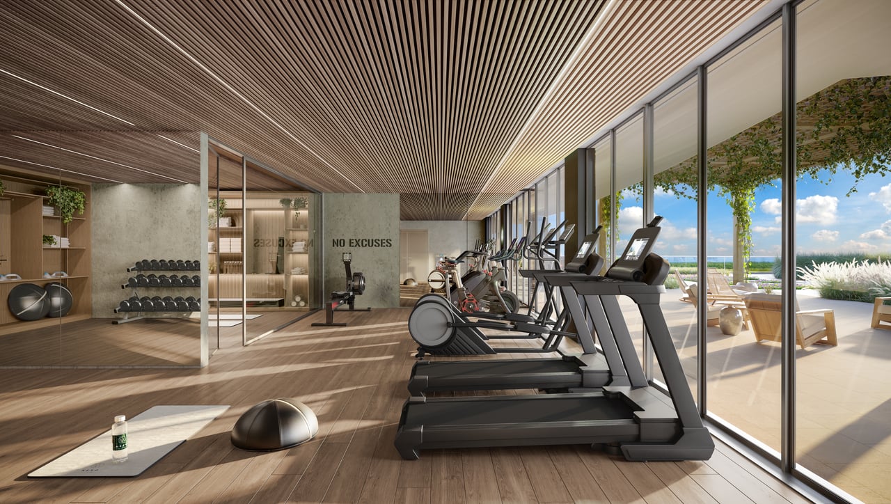 NEXO Residences gym with treadmills facing floor-to-ceiling windows and a sunny terrace.