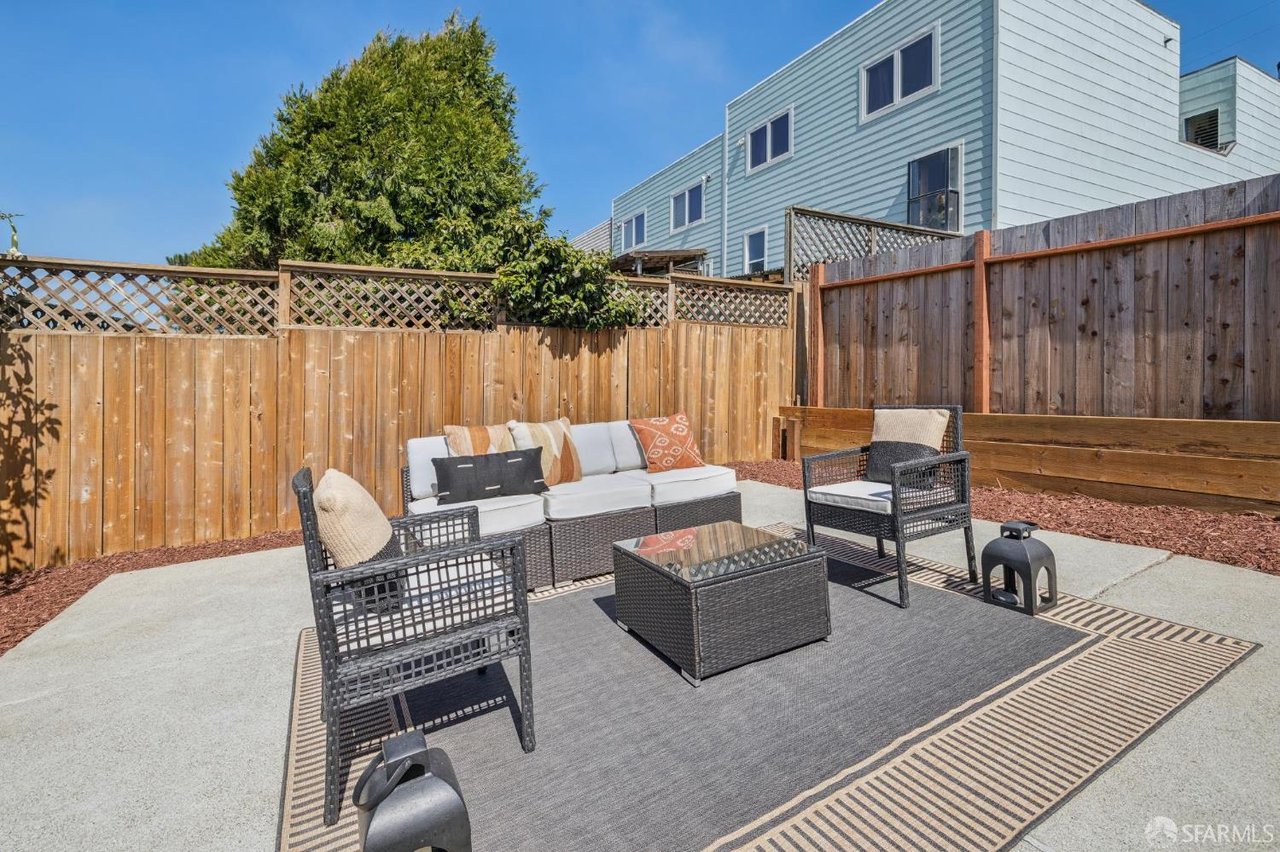 Furnished backyard patio with wicker seating, an outdoor rug, and tall wooden privacy fences.