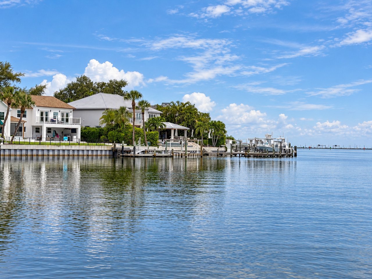 Beach Park waterfront homes and private docks line a calm canal beneath a blue sky.