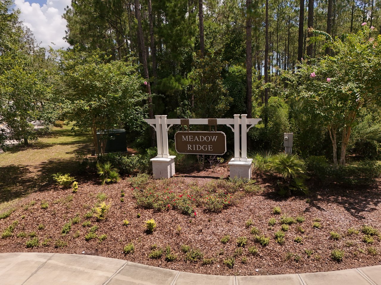 Meadow Ridge entrance sign among trees and landscaped plantings.