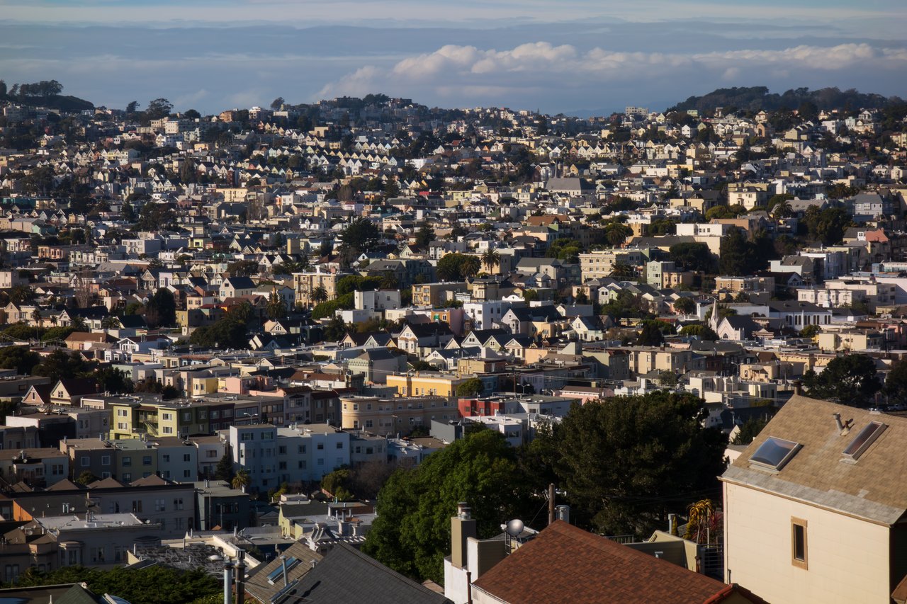Aerial view of San Francisco’s Noe Valley neighborhood, highlighting rows of charming residential homes nestled along the hillside with a clear view of tree-lined streets and rolling terrain.