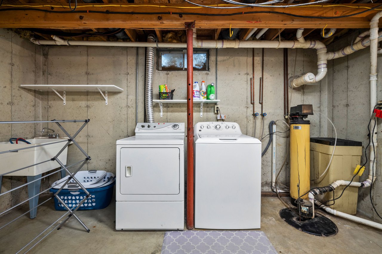 Basement laundry room with a washer and dryer beside a utility sink and water heater.