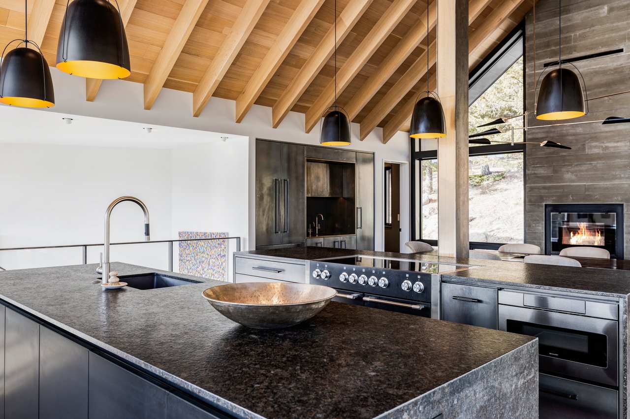 Luxury Boulder kitchen featuring dark stone countertops, professional range, and built-in fireplace with mountain views