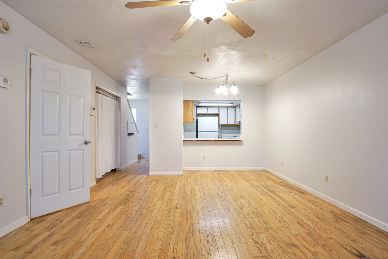 A well-lit room featuring a ceiling fan and polished hardwood floors, creating a warm and inviting atmosphere.