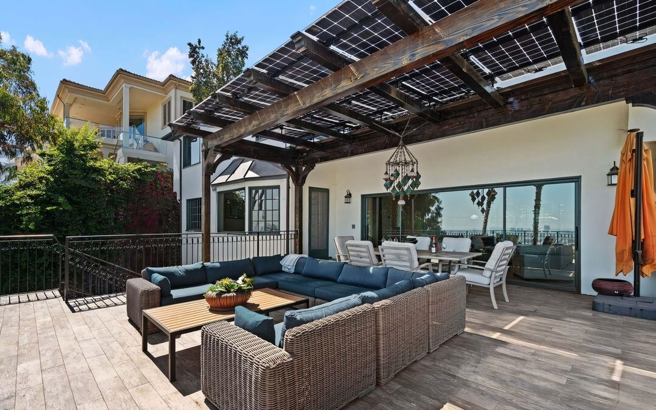 An expansive outdoor patio featuring a large woven sectional sofa with blue cushions and a matching coffee table.