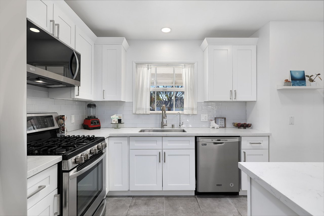 Double sink with window overlooking backyard and bright white cabinetry in updated Lake Balboa kitchen