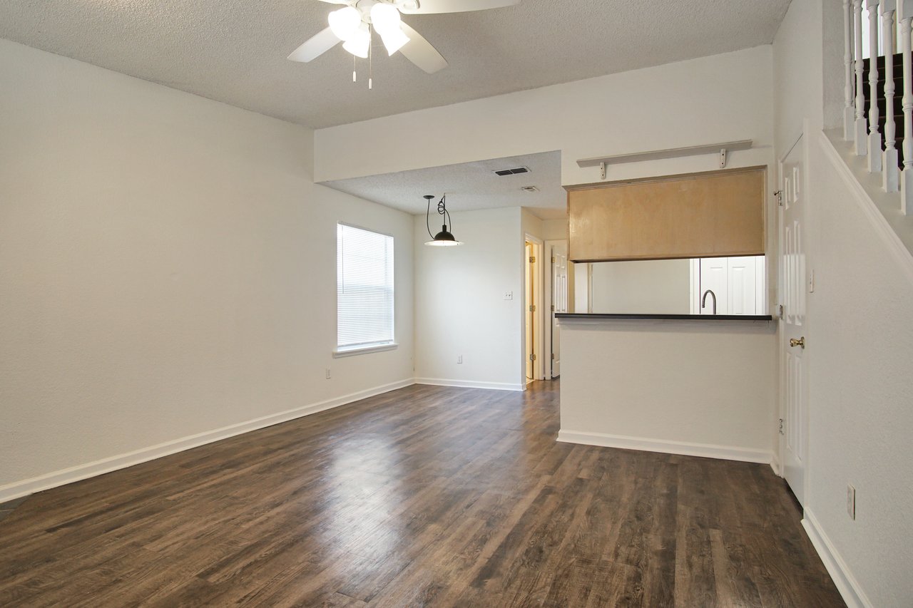 An empty room featuring hardwood floors and a ceiling fan, creating a spacious and airy atmosphere.