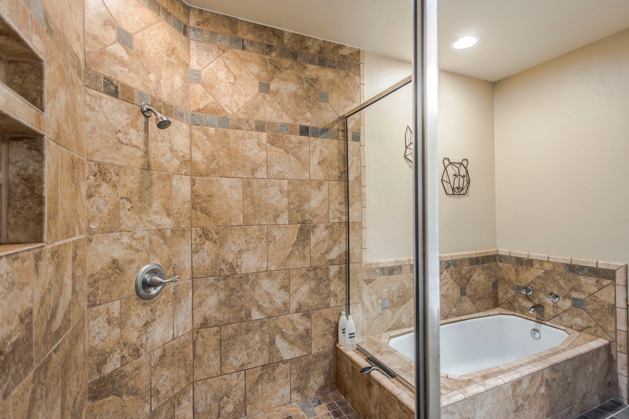 Bathroom with a tiled glass shower beside a built-in bathtub.