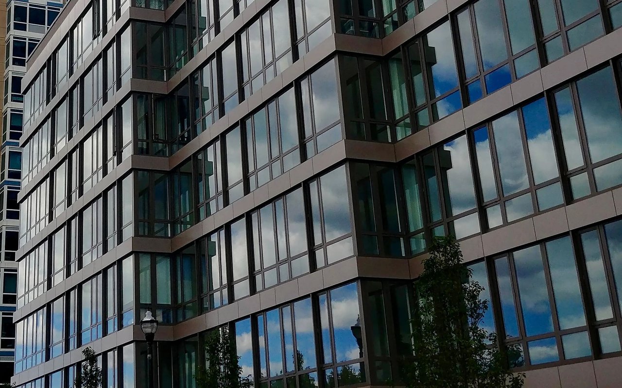 Modern high-rise condominium facade with large reflective windows and horizontal bands.