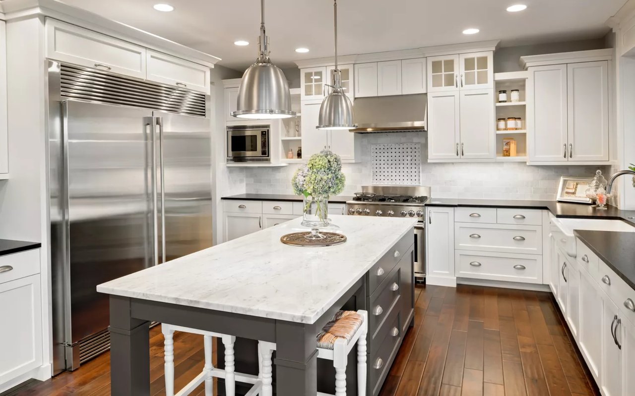 Bright kitchen with white cabinets, stainless steel appliances, and a large marble-topped island.