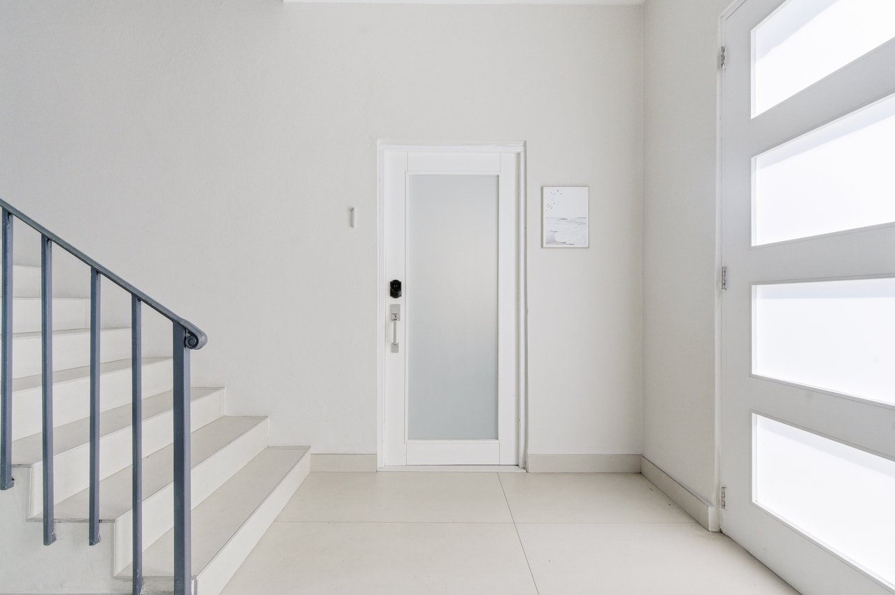 Bright entryway with a frosted-glass door, staircase, and large glazed front door.