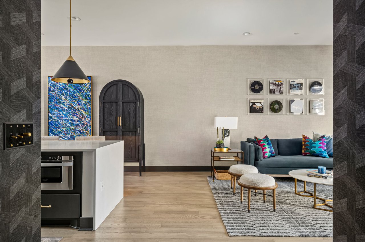 Open kitchen and living great room at 4507 Unity Circle in The Grove, Austin, with a curated gallery wall and hardwood floors, designed by Ashley Walker Designs.