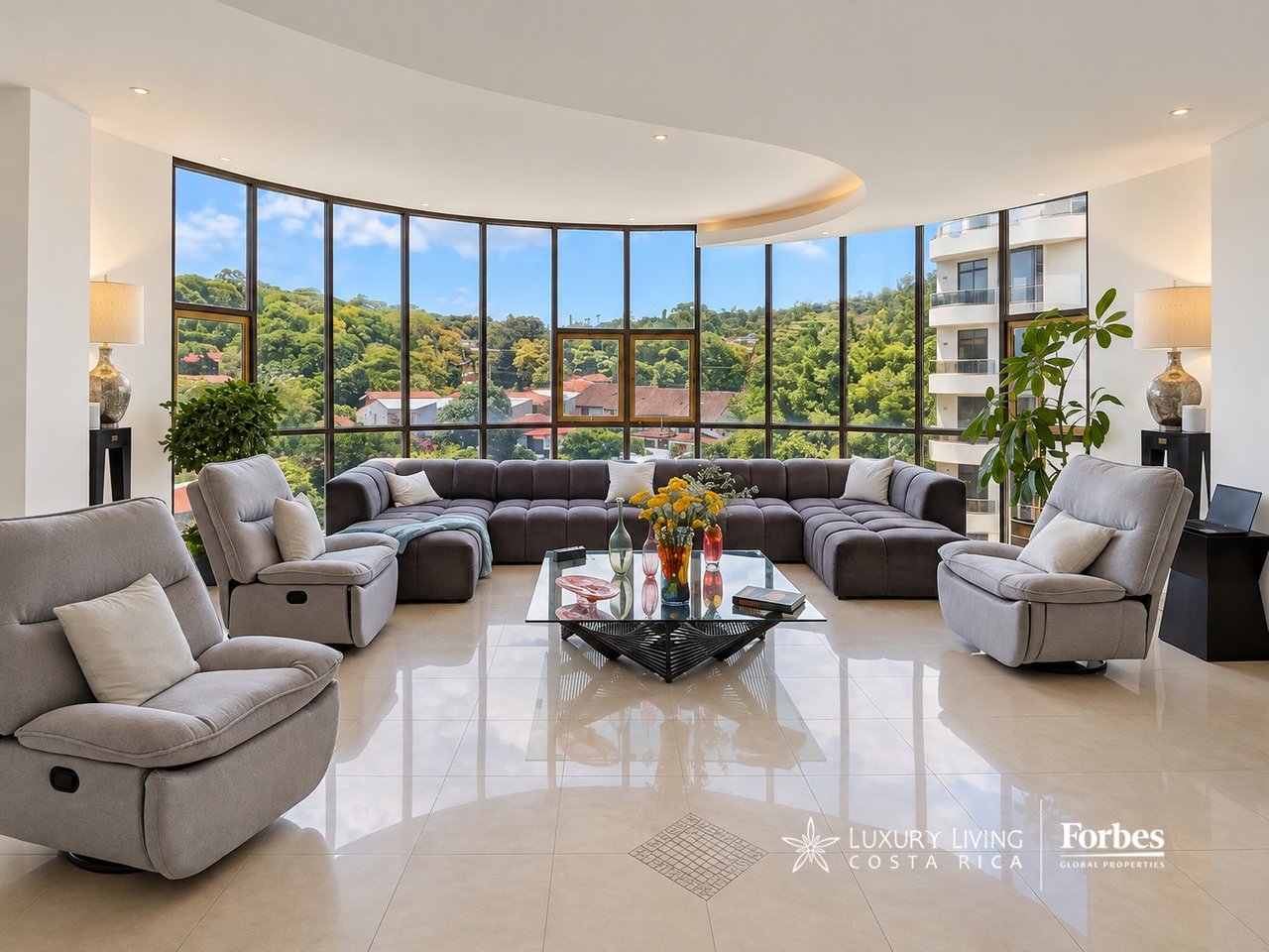 Living room with curved gray sectional and floor-to-ceiling windows overlooking green hills.