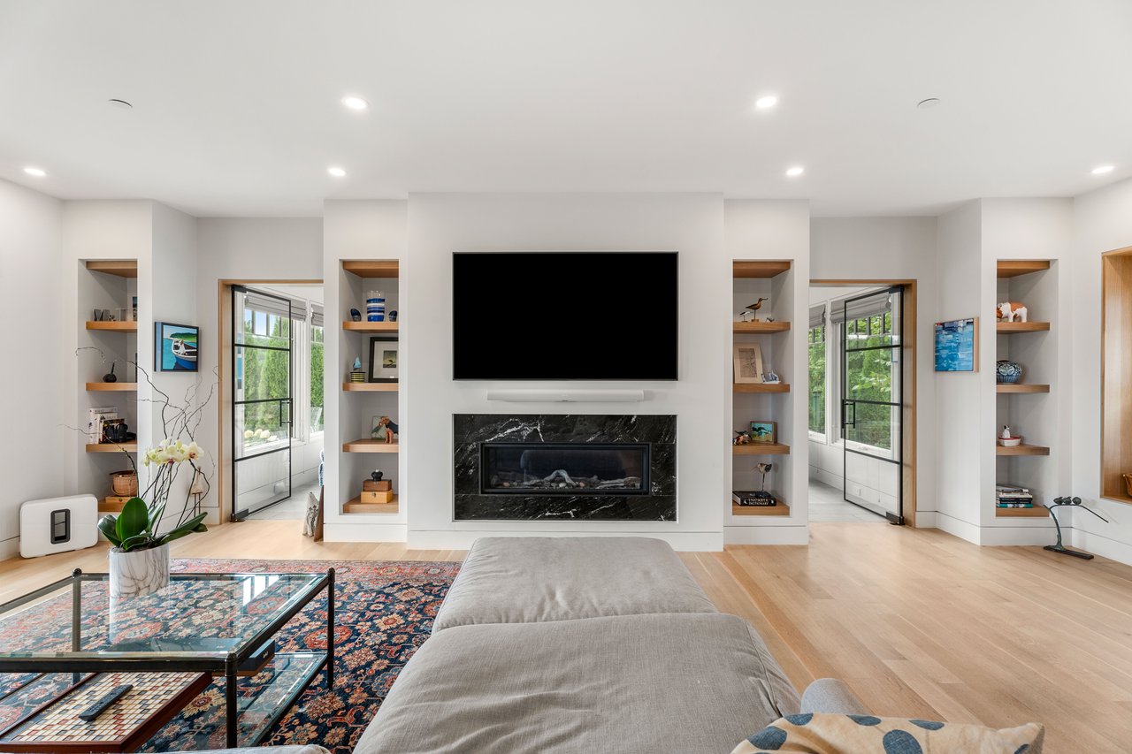 Living room with marble fireplace, built-in shelves, and glass doors to a sunroom.