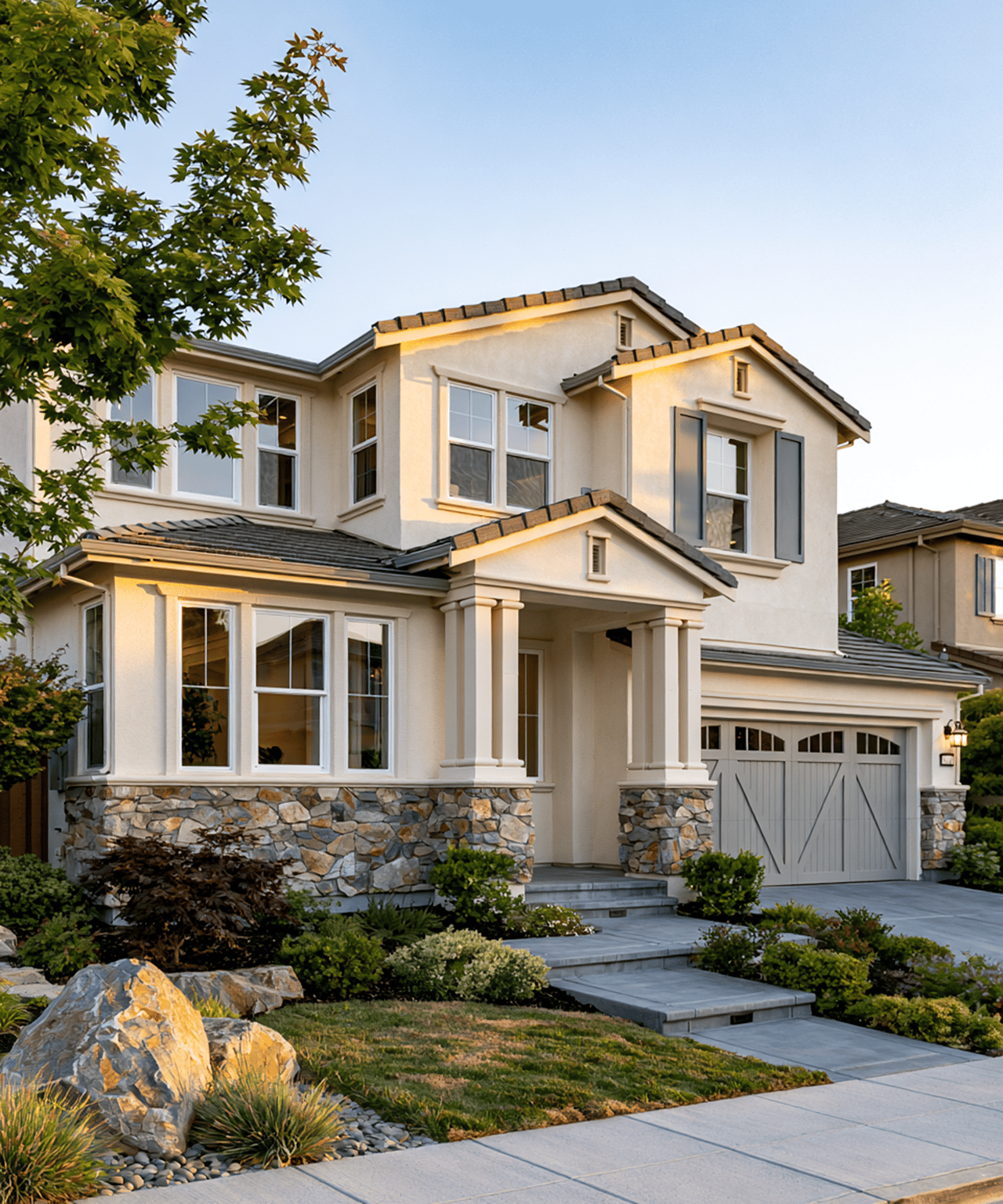 Two-story stucco home with stone accents, covered entry, attached garage, and landscaped front yard.