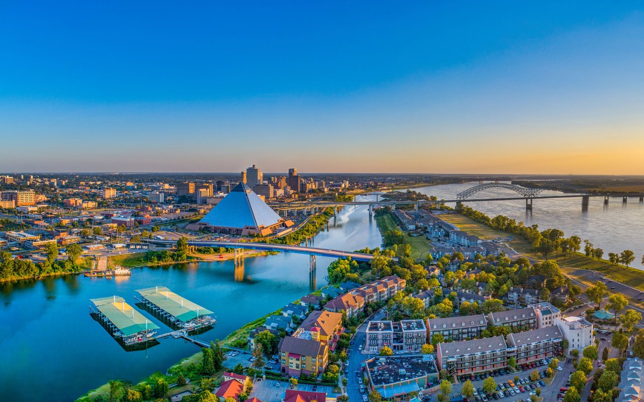 Memphis skyline and Pyramid beside the Mississippi River, with bridges and waterfront neighborhoods at golden hour.