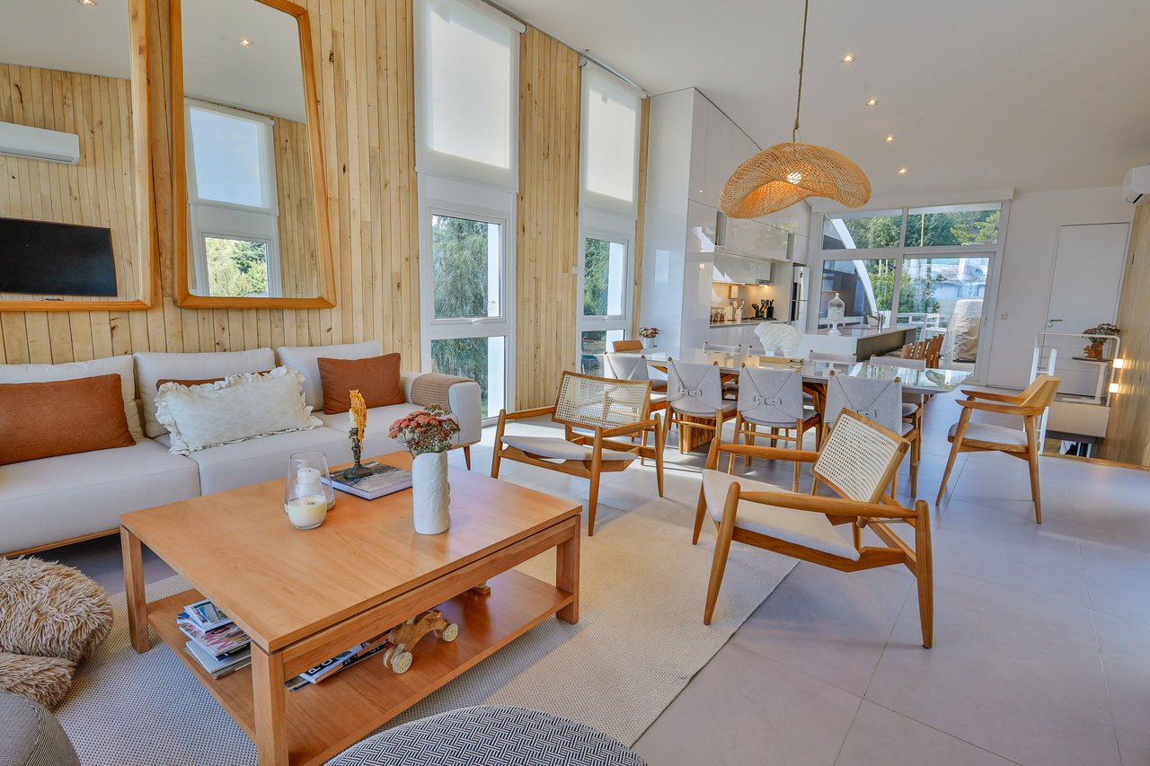 Open-plan living and dining room with a white sofa, wood furniture, and tall windows.