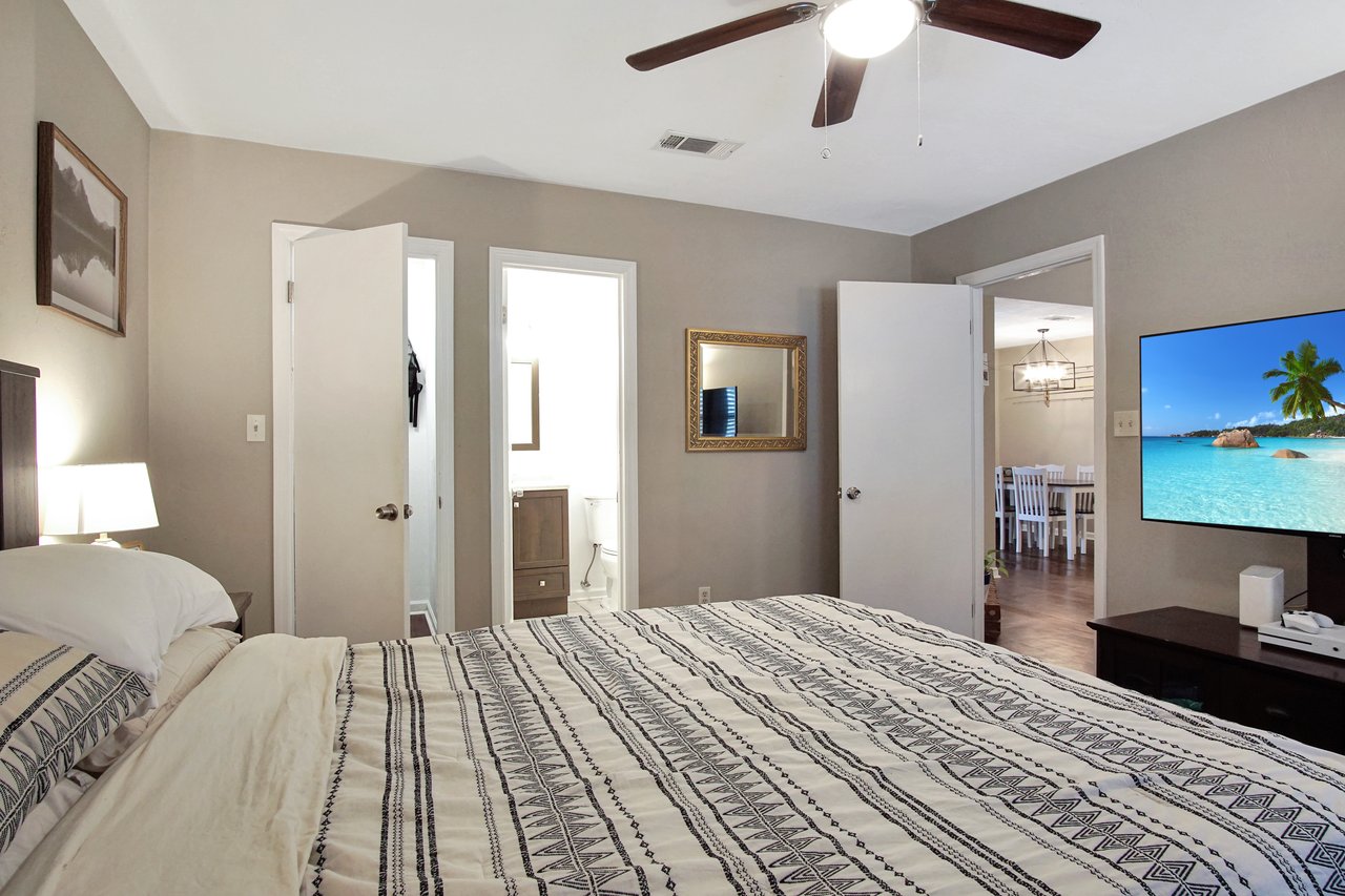 A cozy bedroom featuring a comfortable bed and a television mounted on the wall.