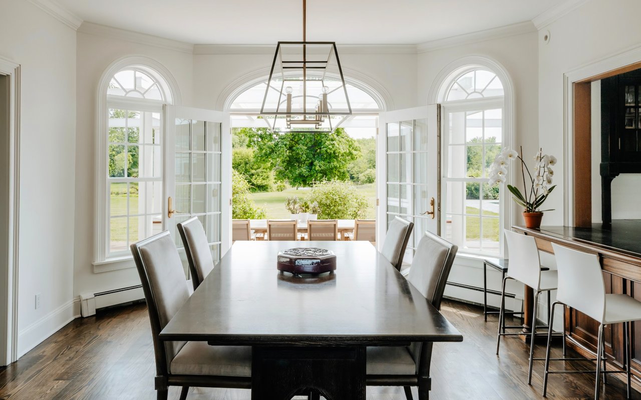  A formal dining room features a long, dark wood table with six light grey upholstered chairs. 