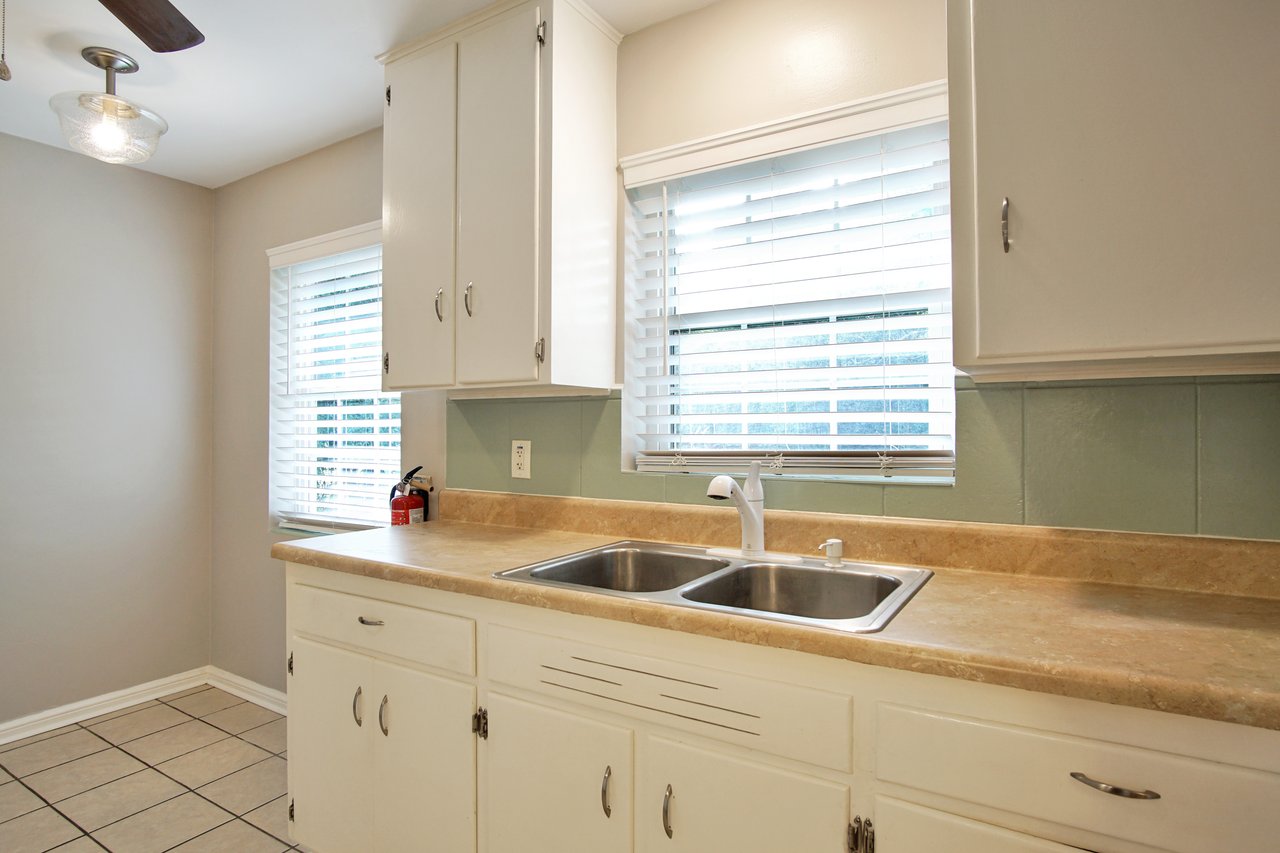 A modern kitchen featuring a sink and a ceiling fan, showcasing a clean and functional design.