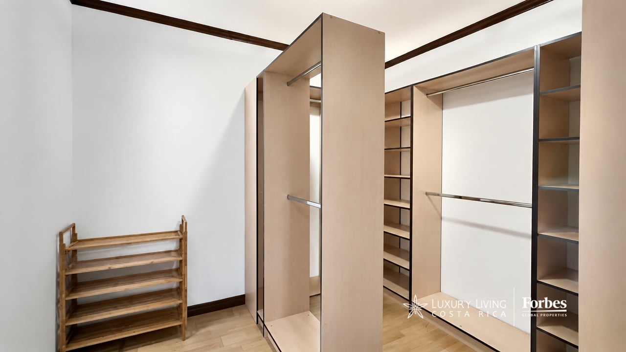 Walk-in closet with light wood built-in shelving, hanging rails, and a wooden shoe rack.