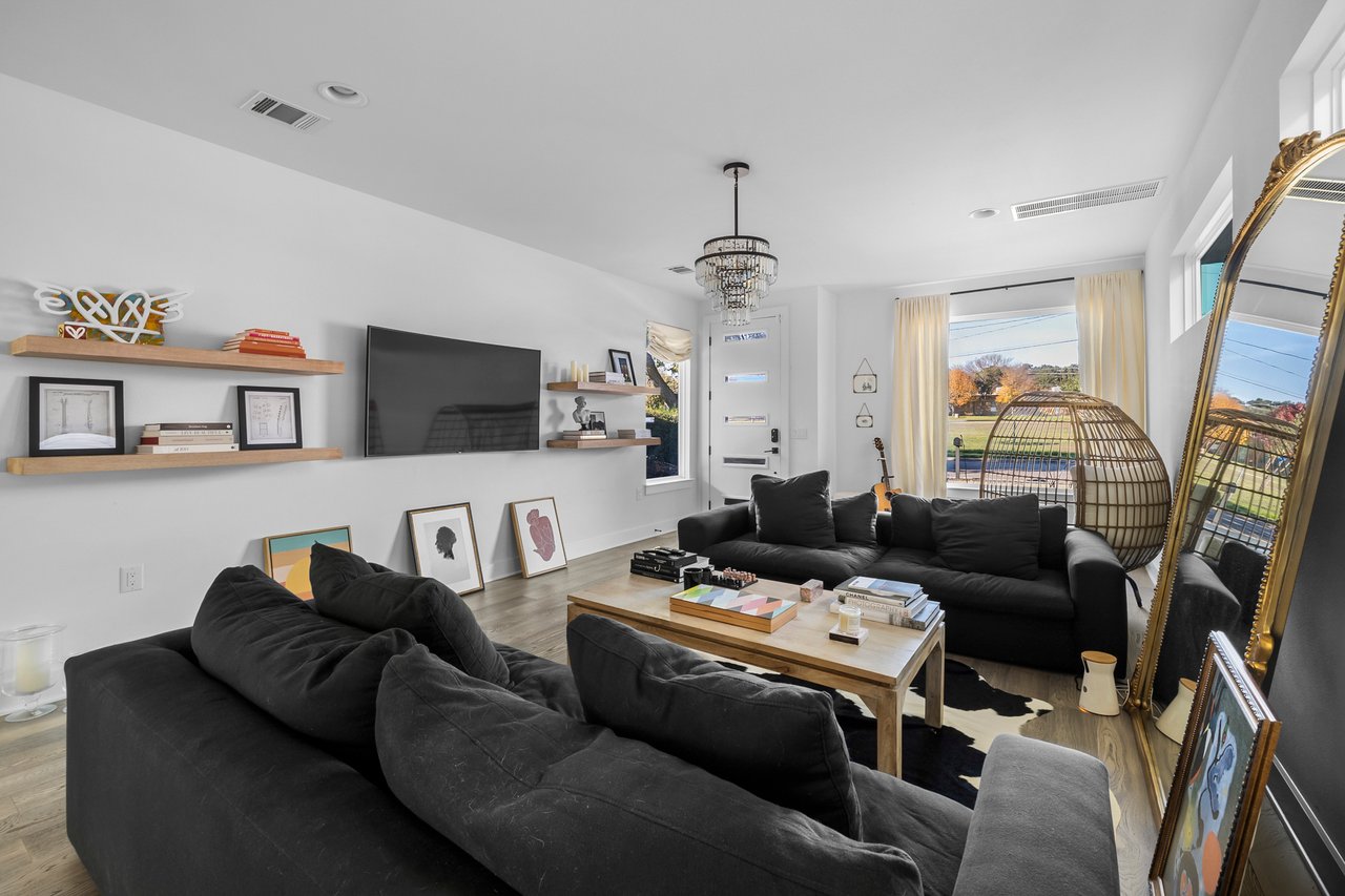 Living room in a modern Dawson-area home at 404 Powell Cir Unit B, Austin, showing a charcoal sectional sofa, cowhide rug, and a tall gold-framed floor mirror.
