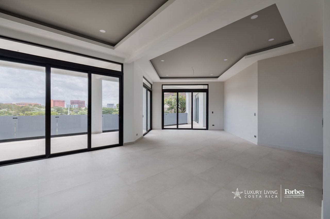 Vacant apartment living area with recessed ceiling and sliding glass doors opening to a balcony.
