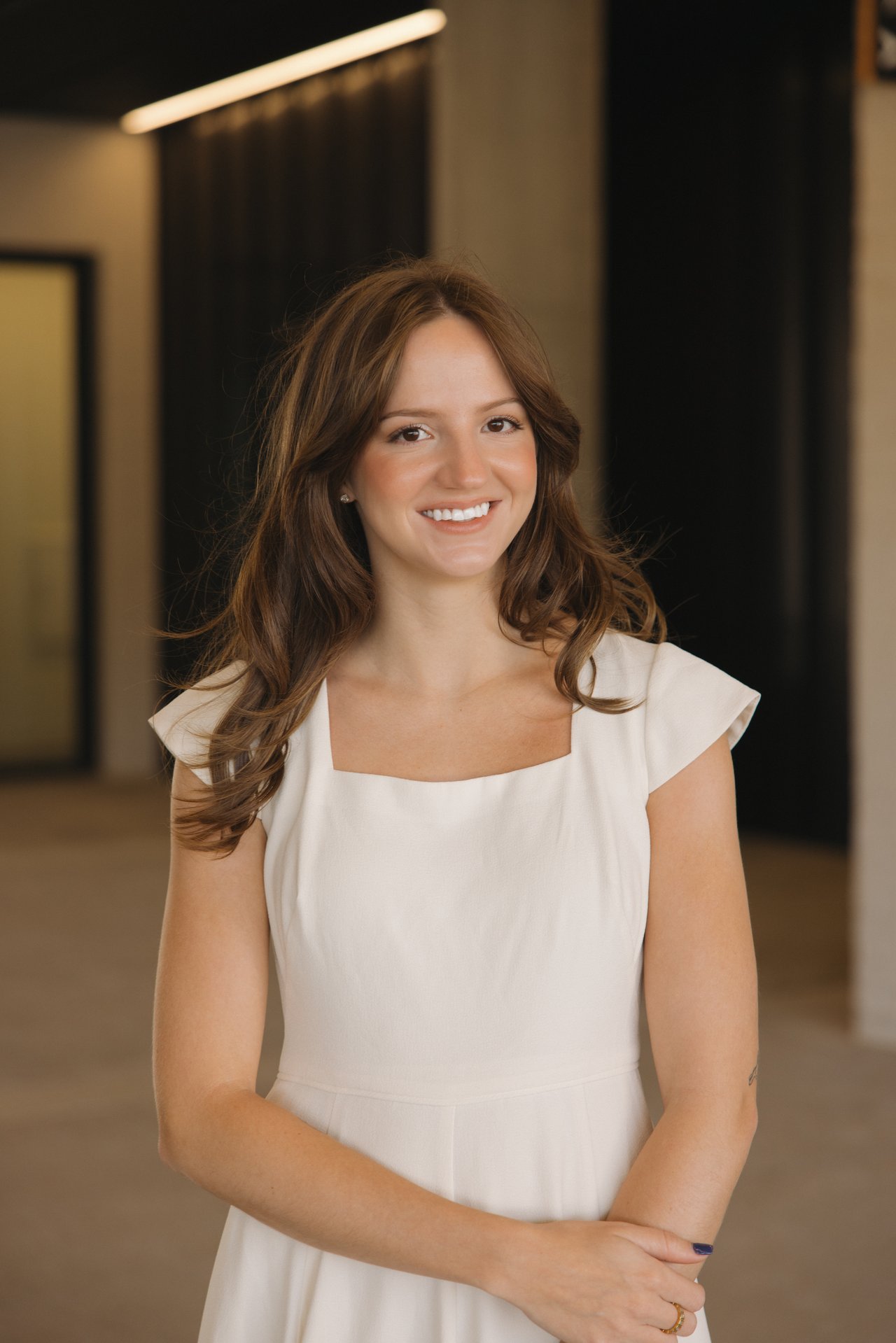 Hannah Turner smiling in a white dress, with long brown hair.