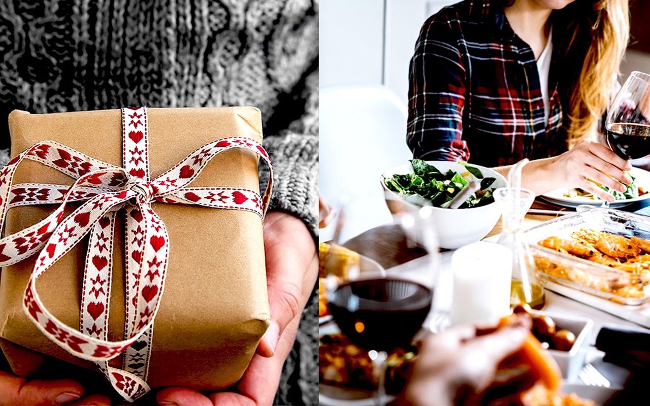 Hands hold a ribbon-wrapped holiday gift beside a woman serving food at a dinner table.