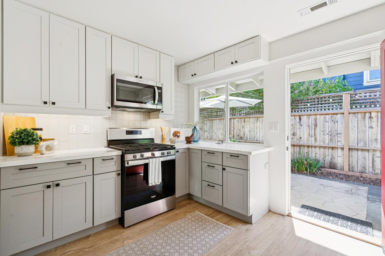Bright white kitchen with shaker cabinets, stainless steel appliances, and a sliding door to the patio.