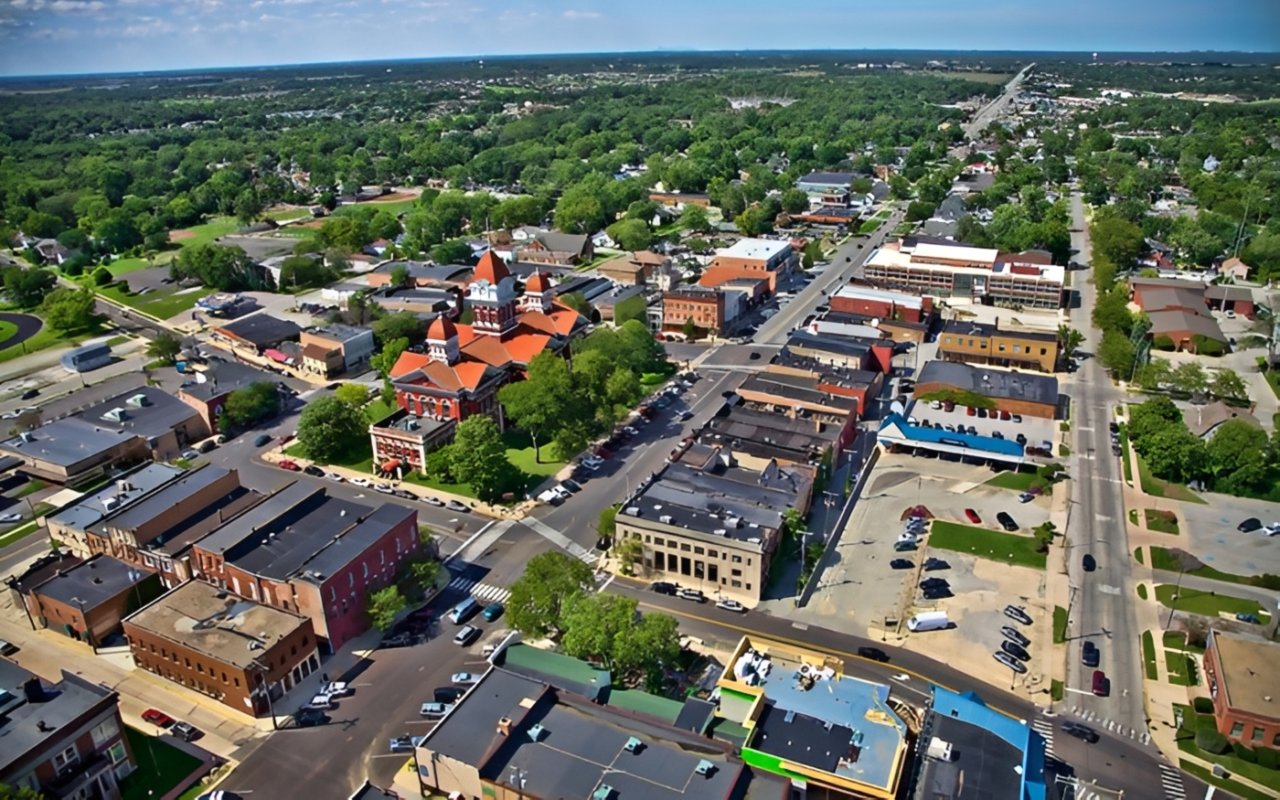 Aerial view of downtown Crown Point, with the red-roofed courthouse square surrounded by shops and tree-lined streets.