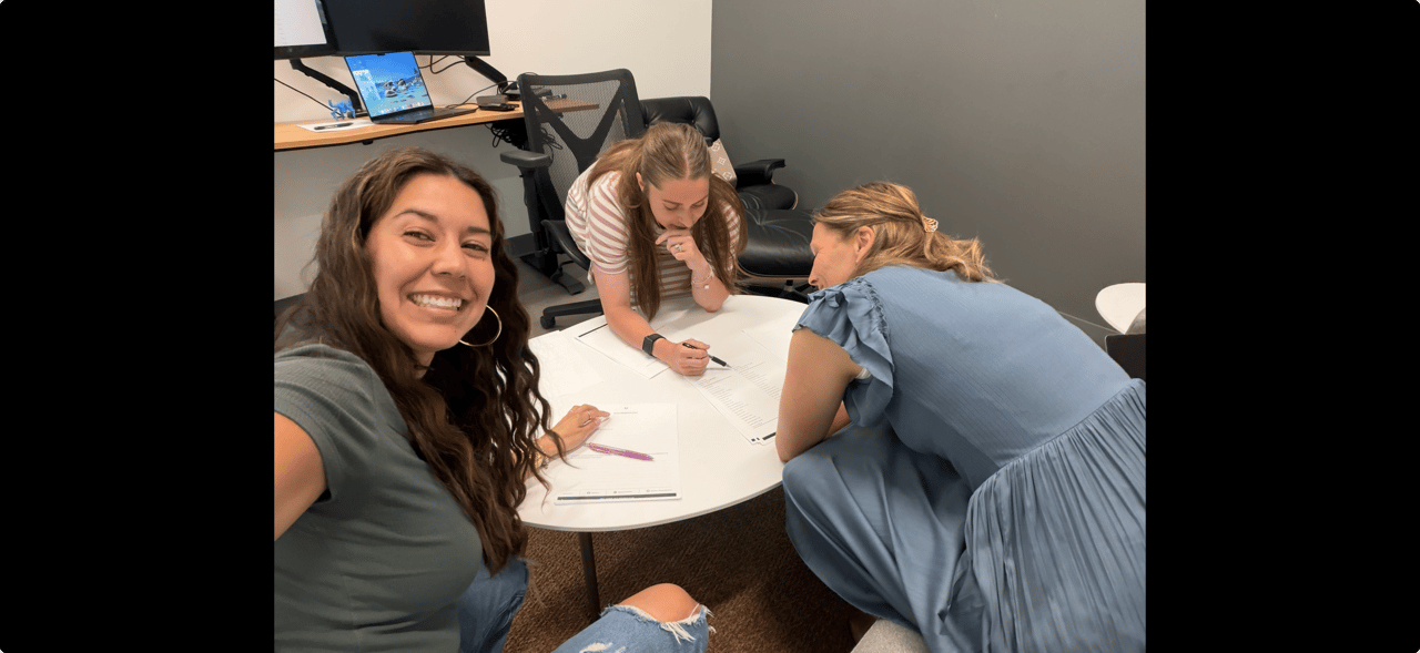 Three Foundry Group team members working together around a table reviewing documents in their office