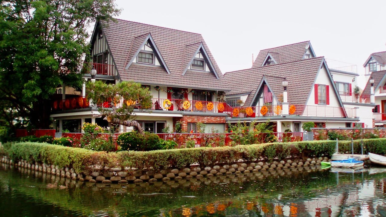 Tudor-style waterfront homes decorated with orange Halloween ornaments along their balconies.