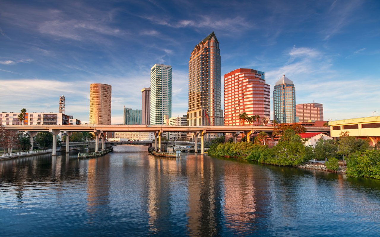 Tampa skyline and bridge reflected in the Hillsborough River at golden hour.