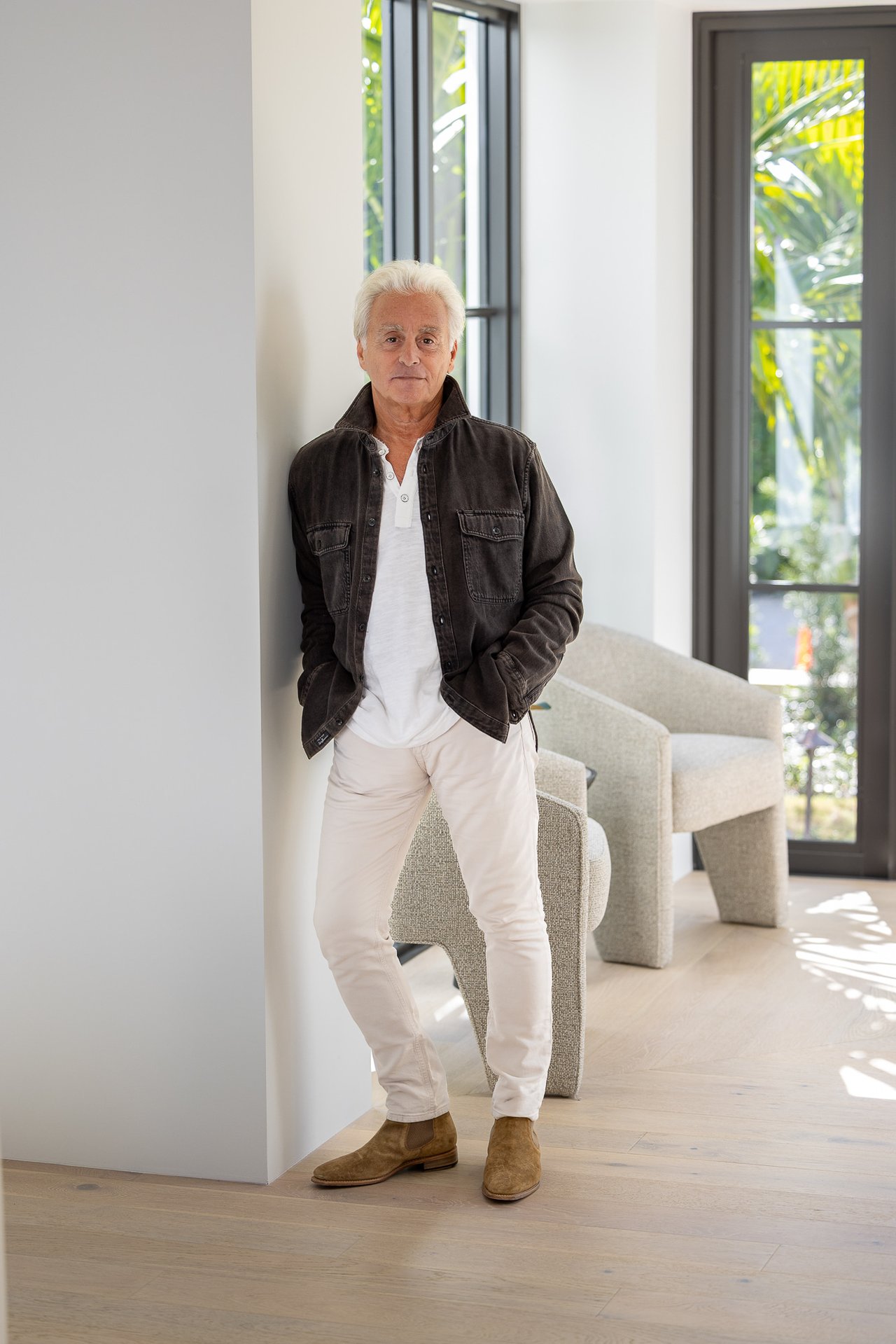 Robert Guntmacher standing beside an upholstered chair in a bright, modern interior.