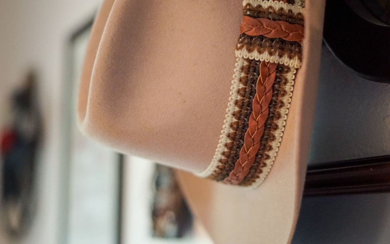 Beige upholstered chair with braided brown leather and woven trim