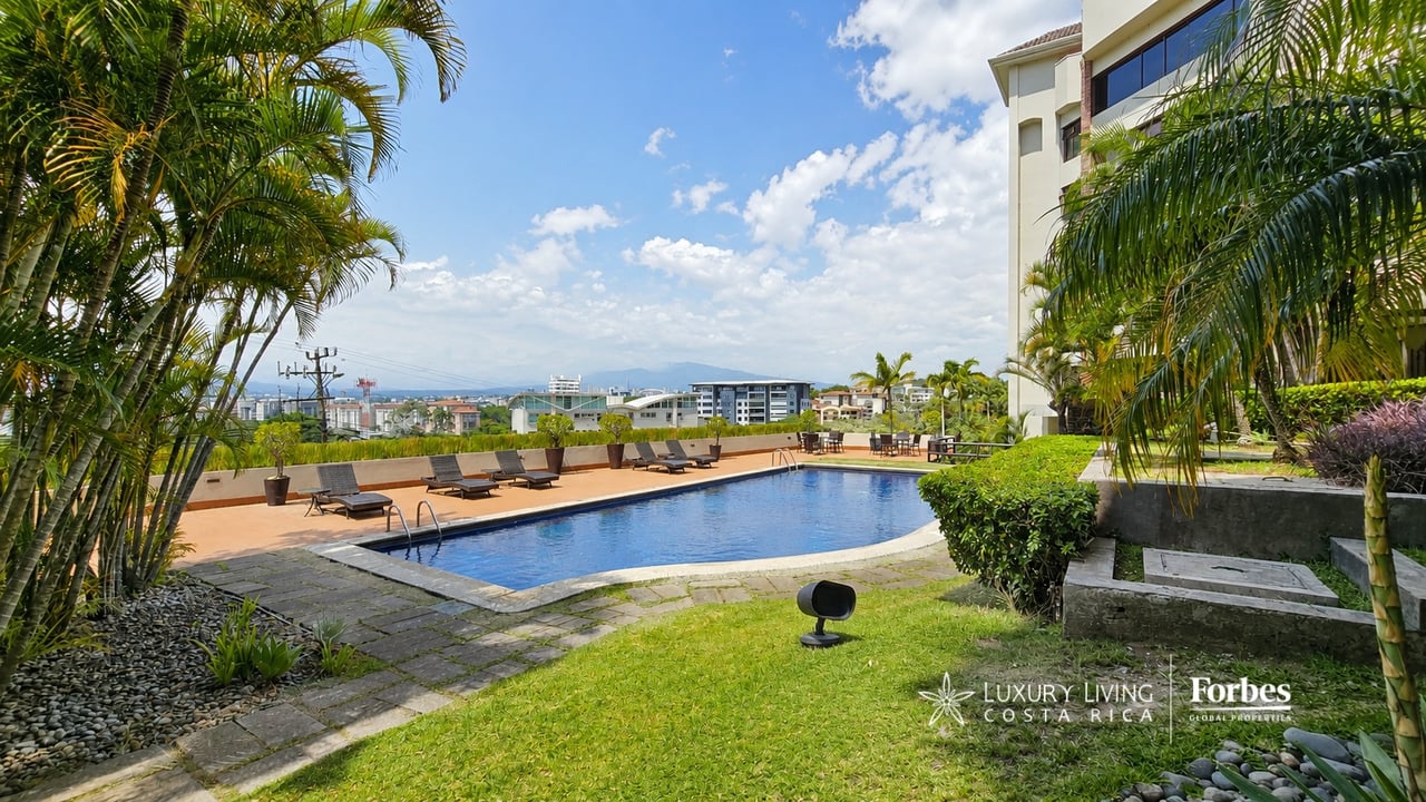 Condominium pool and palm-lined terrace with city and distant mountain views.