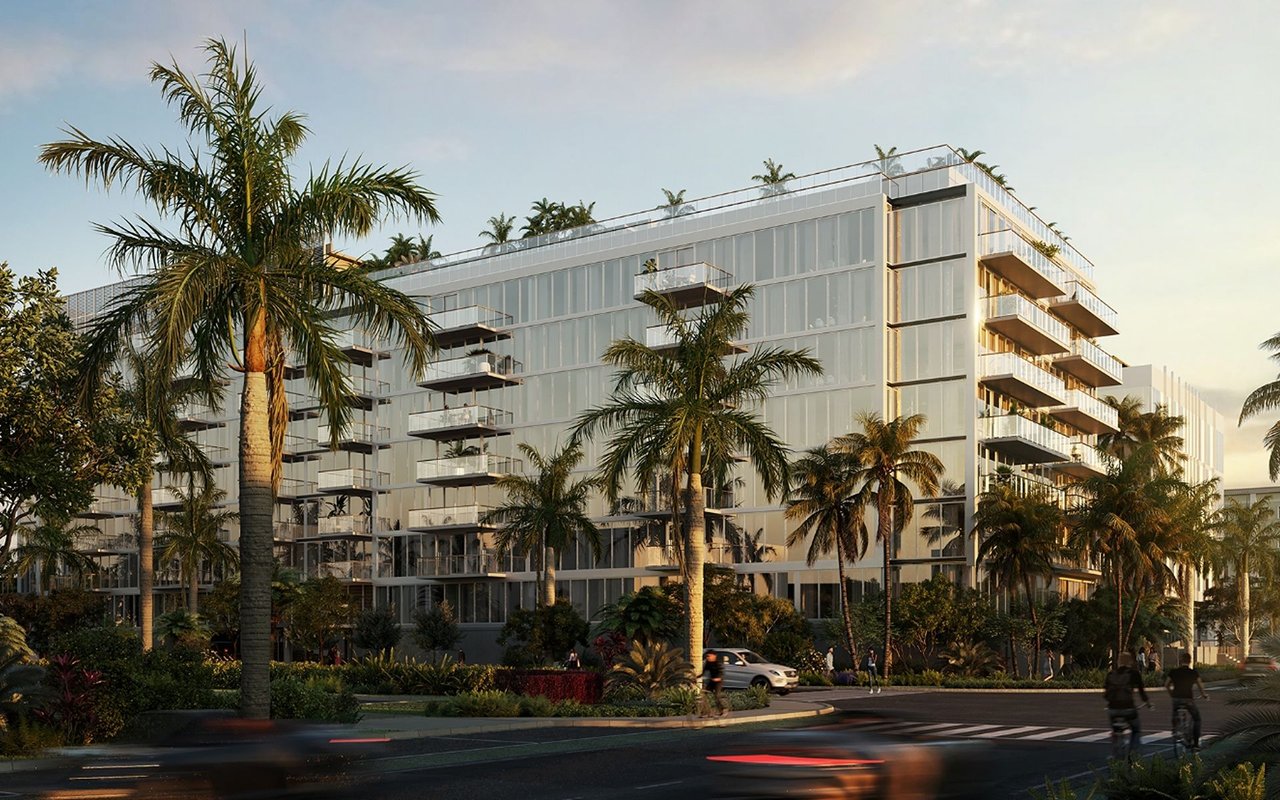 Modern glass residential building with balconies, palm trees, and landscaped grounds.