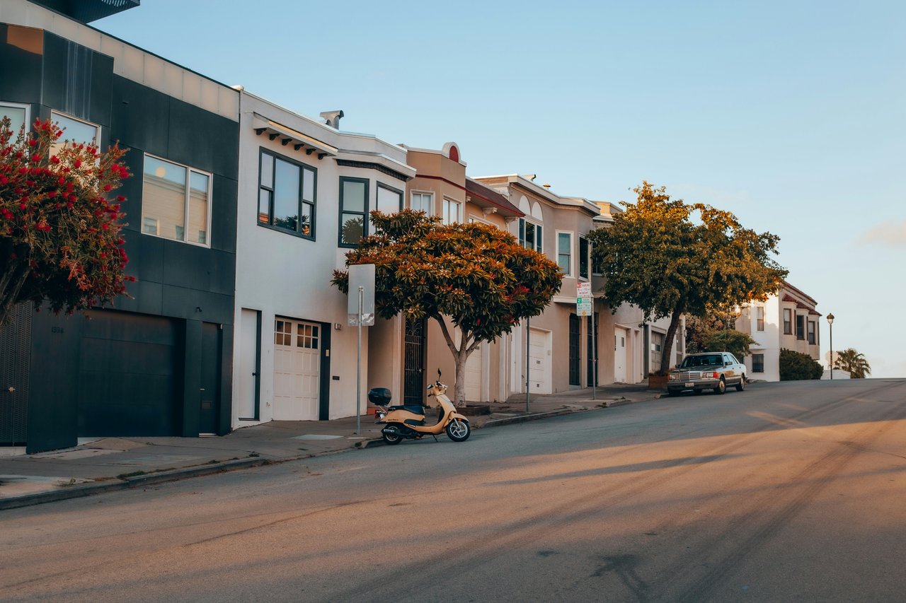 Row of stucco San Francisco homes with ground-floor garages along a quiet residential street at sunset