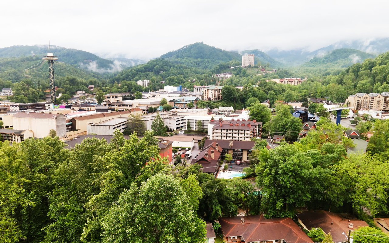 Mountain town with clustered buildings and homes beneath misty, forested ridges.