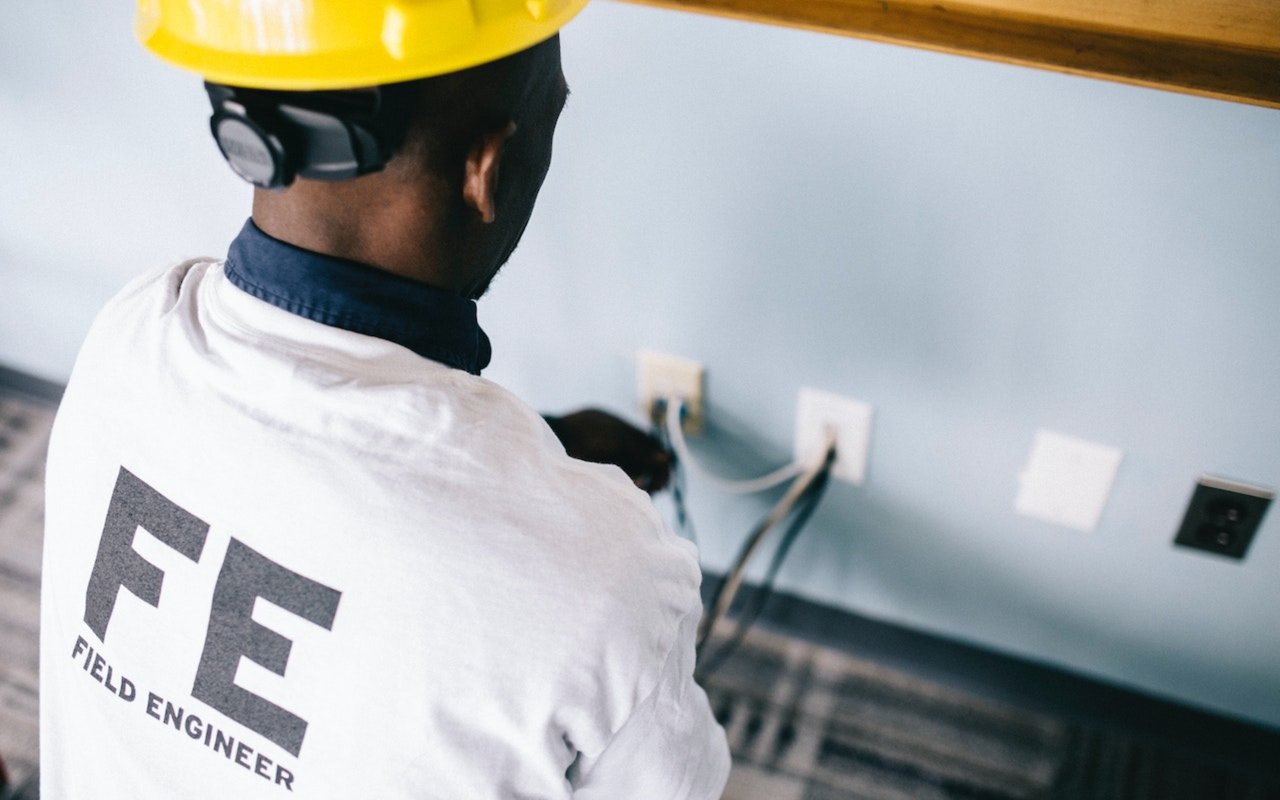 Field engineer in a yellow hard hat working on electrical outlets