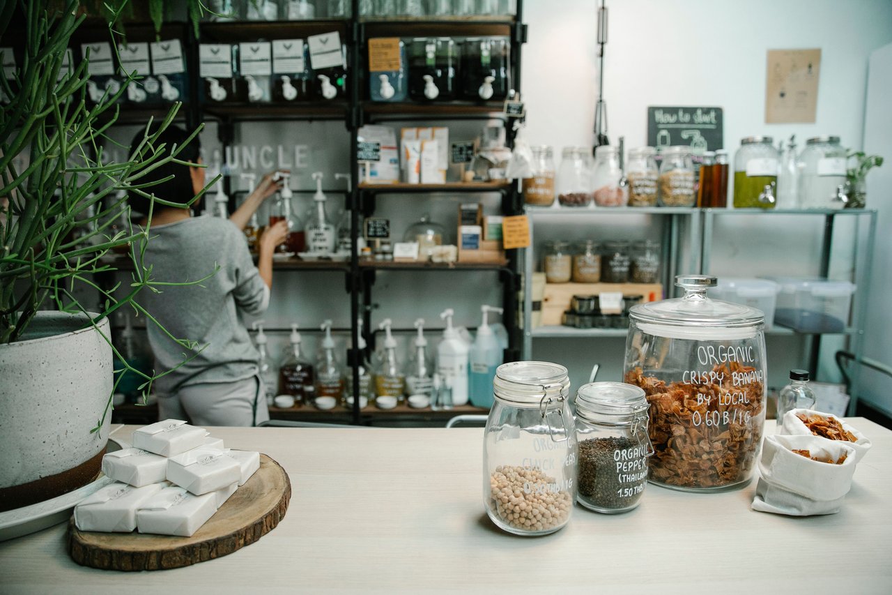 Customer browsing bulk goods in a shop, with jars of snacks displayed on the counter.