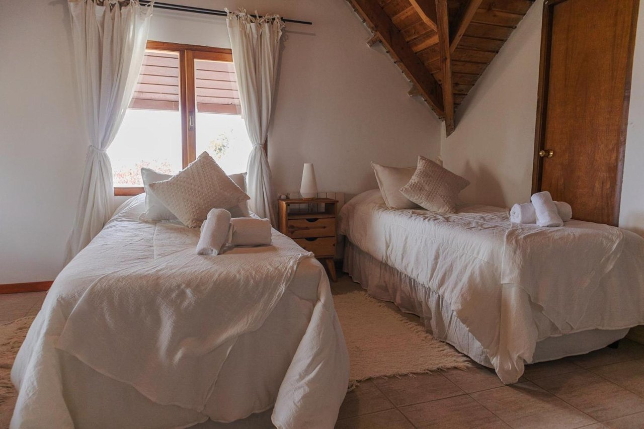 Bedroom with two single beds, white linens, and an exposed timber ceiling.