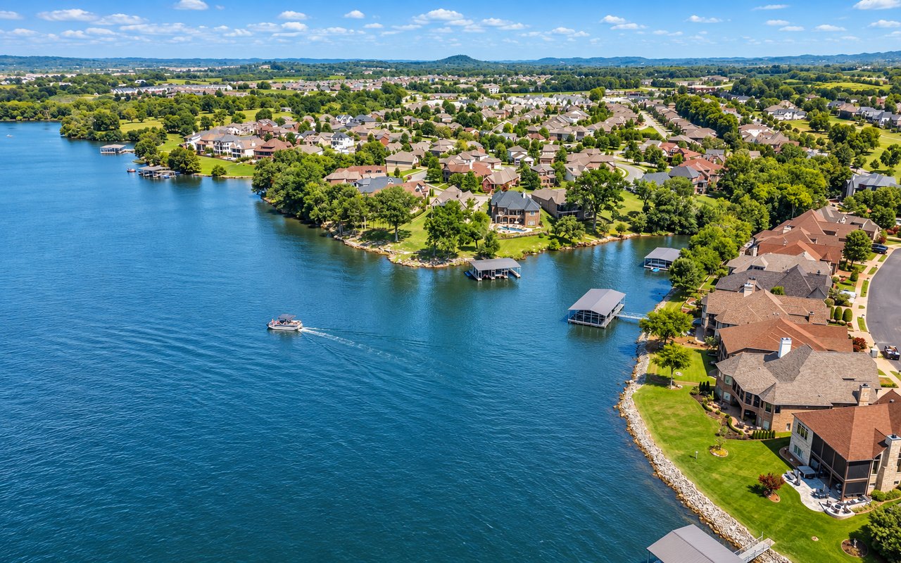 Aerial view of lakeside homes with private docks and a boat on the water.