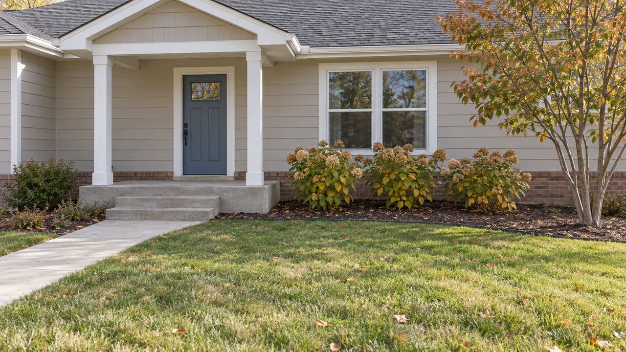 A newer ranch home's covered entry, beige lap siding and paired front window above a broad lawn and concrete approach.