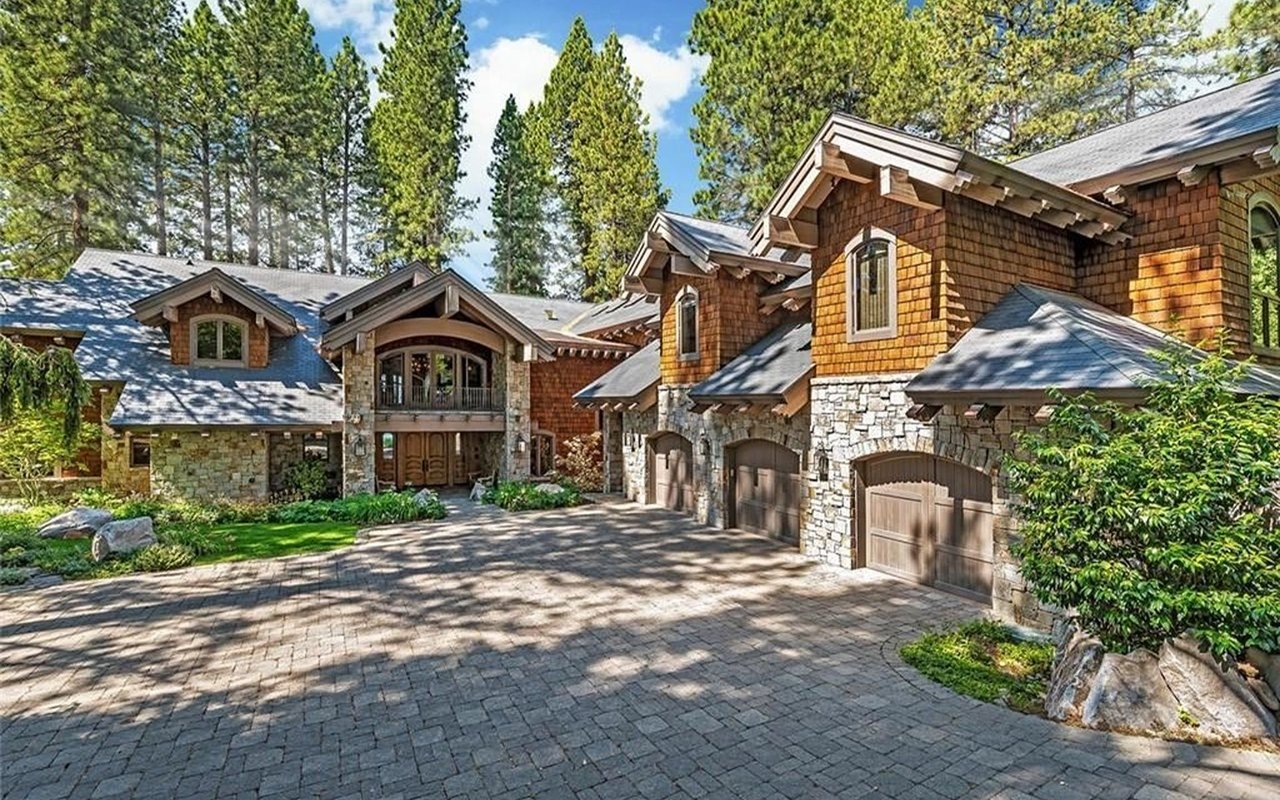 Mountain-style home with stone and cedar-shingle exterior, multiple garages, and a broad paved driveway.
