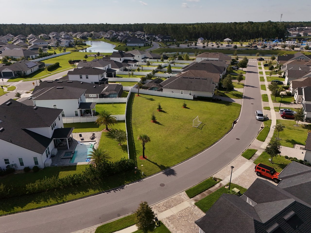 Aerial view of Silverleaf Village homes, with a pond, backyard pools, and a curved residential street.