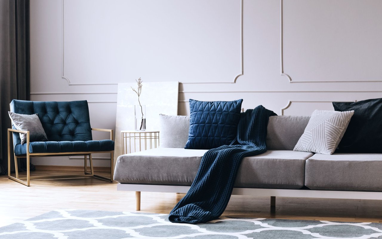 Living room with a gray sectional, blue tufted armchair, and navy throw.